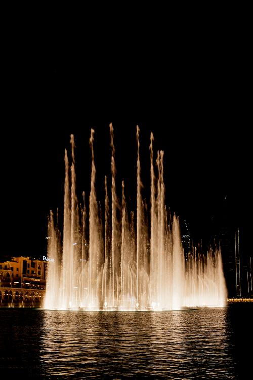 Free Elegant nighttime fountain display with illuminated water jets in an urban setting. Stock Photo