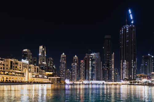 Free Illuminated skyscrapers reflecting on Dubai's waterfront at night. Stock Photo
