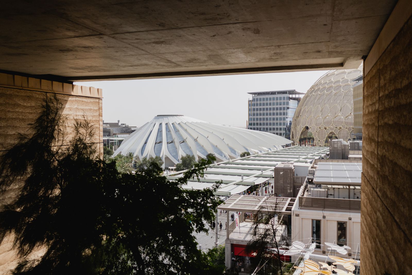 Pavilion roofs and the Al Wasl dome at Expo City Dubai, framed by a concrete opening