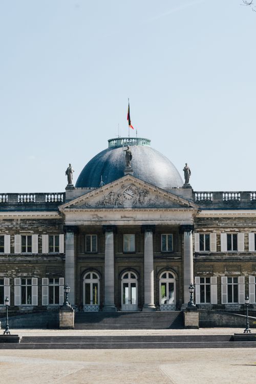 Free Front view of a historic palace facade with a dome under a blue sky. Stock Photo