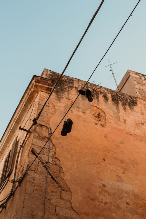 Shoes Hanging from Power Lines by Building Wall