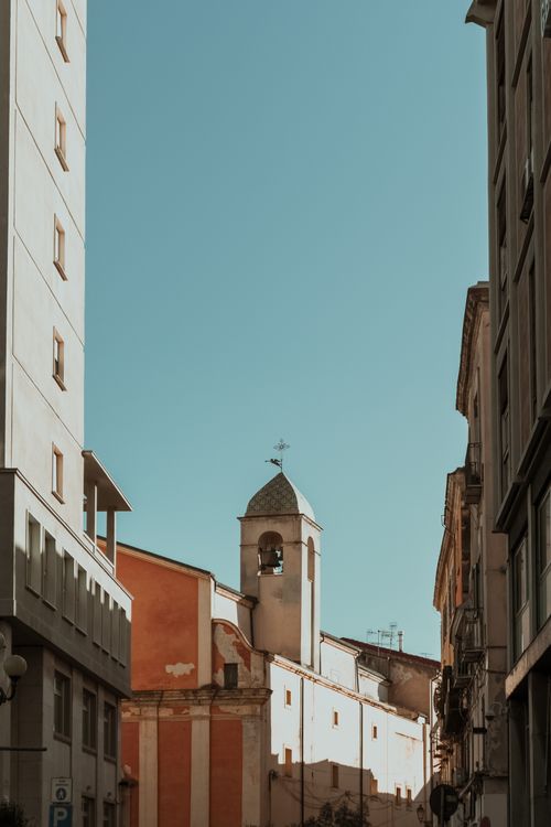 Free Charming European urban scene featuring historic architecture and a prominent bell tower under a clear blue sky. Stock Photo