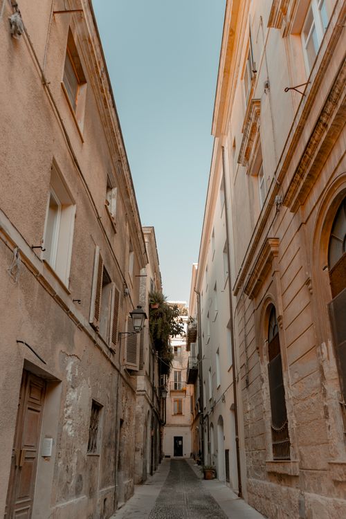 Free Photograph of a narrow alley between historic buildings in an old town, showcasing urban architecture. Stock Photo