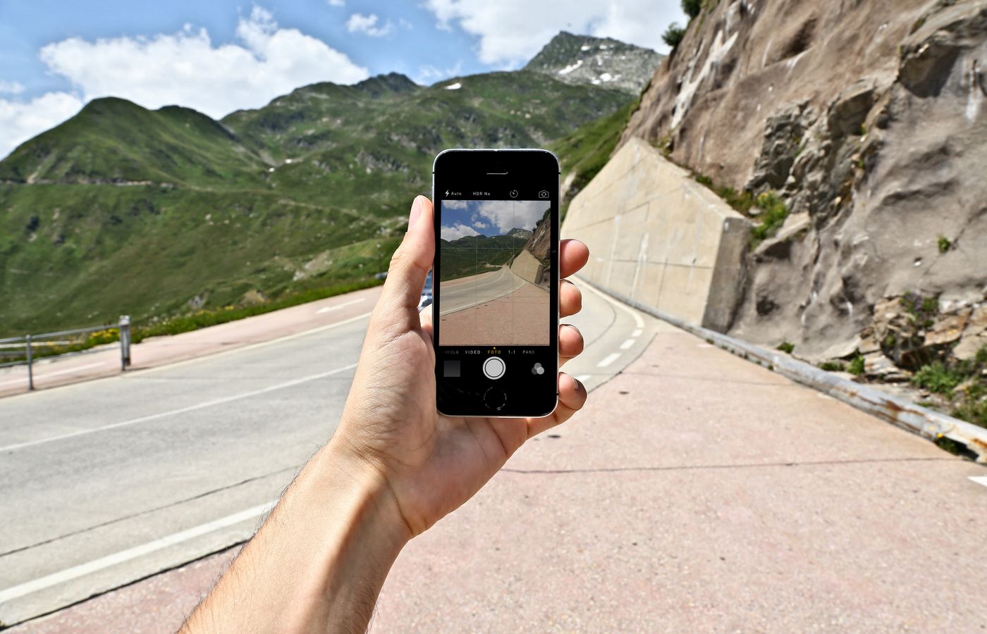 A scenic mountain road captured on a smartphone held in hand. Outdoor mobile photography.