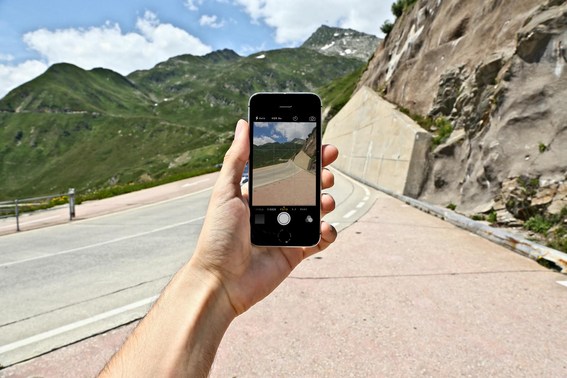 A scenic mountain road captured on a smartphone held in hand. Outdoor mobile photography.