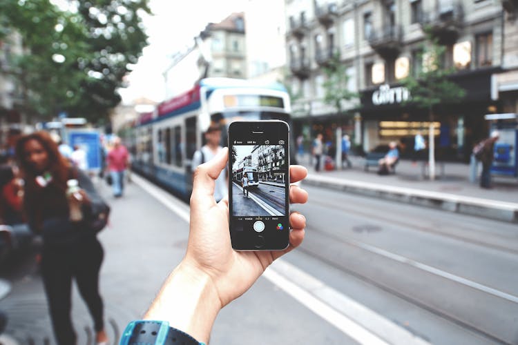 Person Taking A Photo Of A Tram With A Smart Phone