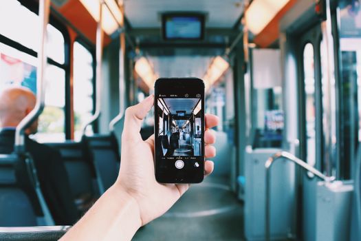 A hand holds a smartphone, capturing the interior of a train, creating a unique visual perspective.