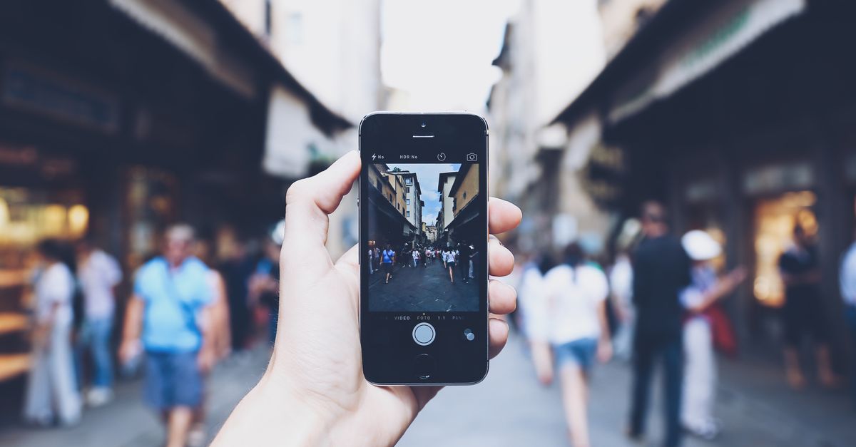 Tourist taking a photo of a crowded landmark with a local market in the background