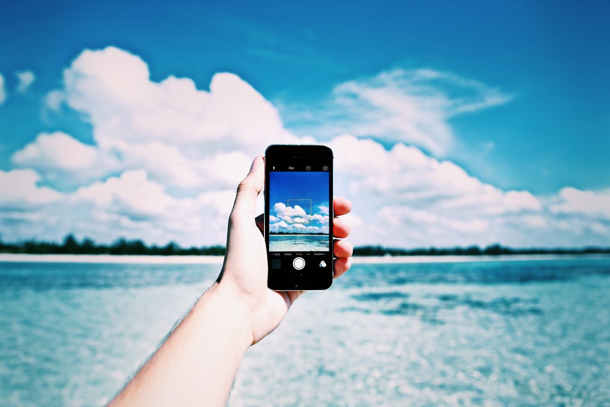 A hand holding a smartphone against open sky, photo by Image Hunter on Pexels