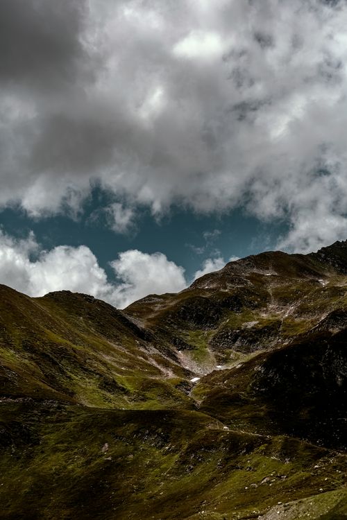 Free A breathtaking view of rugged mountains under a dramatic cloudy sky, perfect for nature enthusiasts. Stock Photo