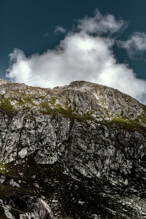 Free Stunning vertical shot of a rocky mountain with blue sky and clouds above. Stock Photo