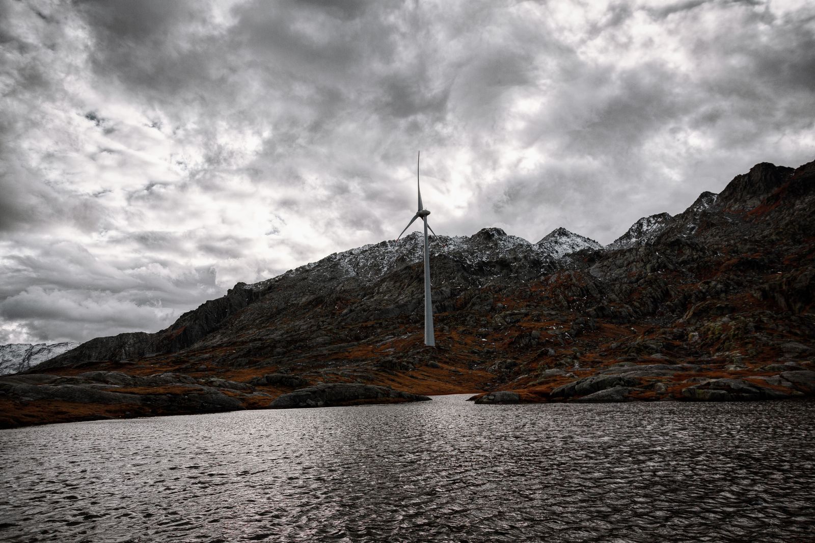 Swiss alpine meadow with wind turbine and snow-capped mountains