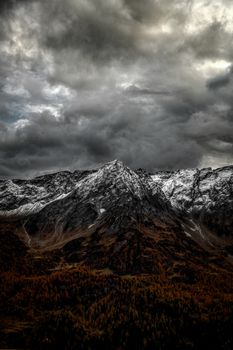 A breathtaking view of the snow-covered Alps with dramatic clouds in Airolo, Switzerland.