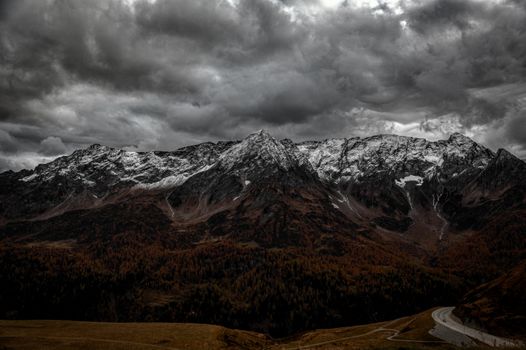 A breathtaking view of snowcapped mountains under a dramatic cloudy sky in Airolo, Switzerland.