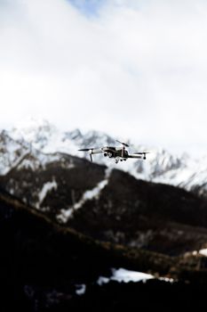A drone captured in midair against a scenic backdrop of snowy mountains.