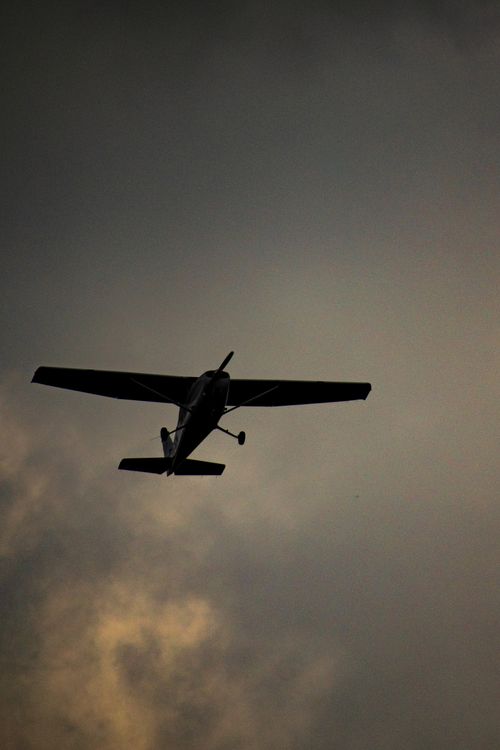 Free A dramatic silhouette of an airplane flying against a cloudy sky during sunset. Stock Photo