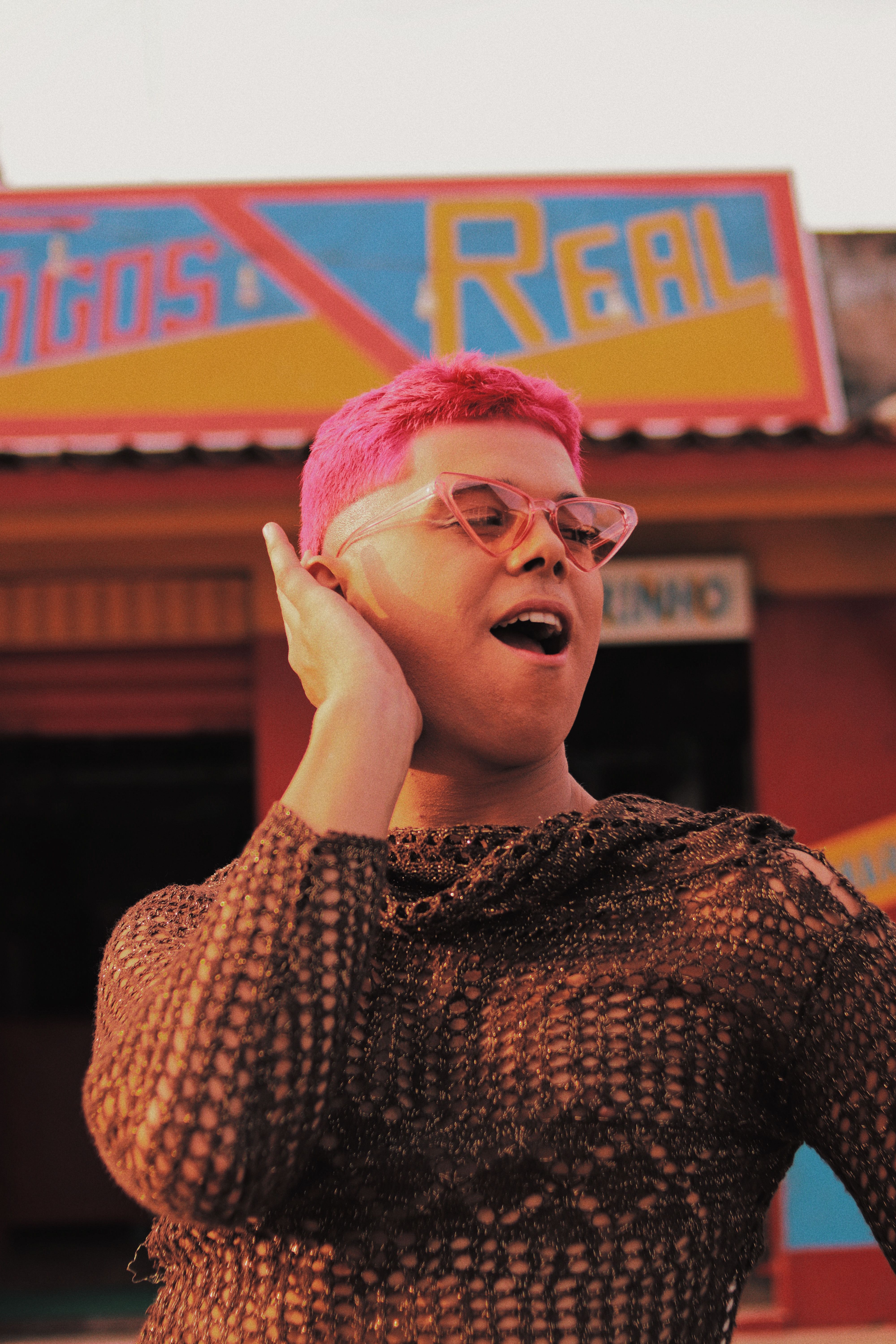 A bold fashion statement with pink hair and unique attire in a lively outdoor setting.