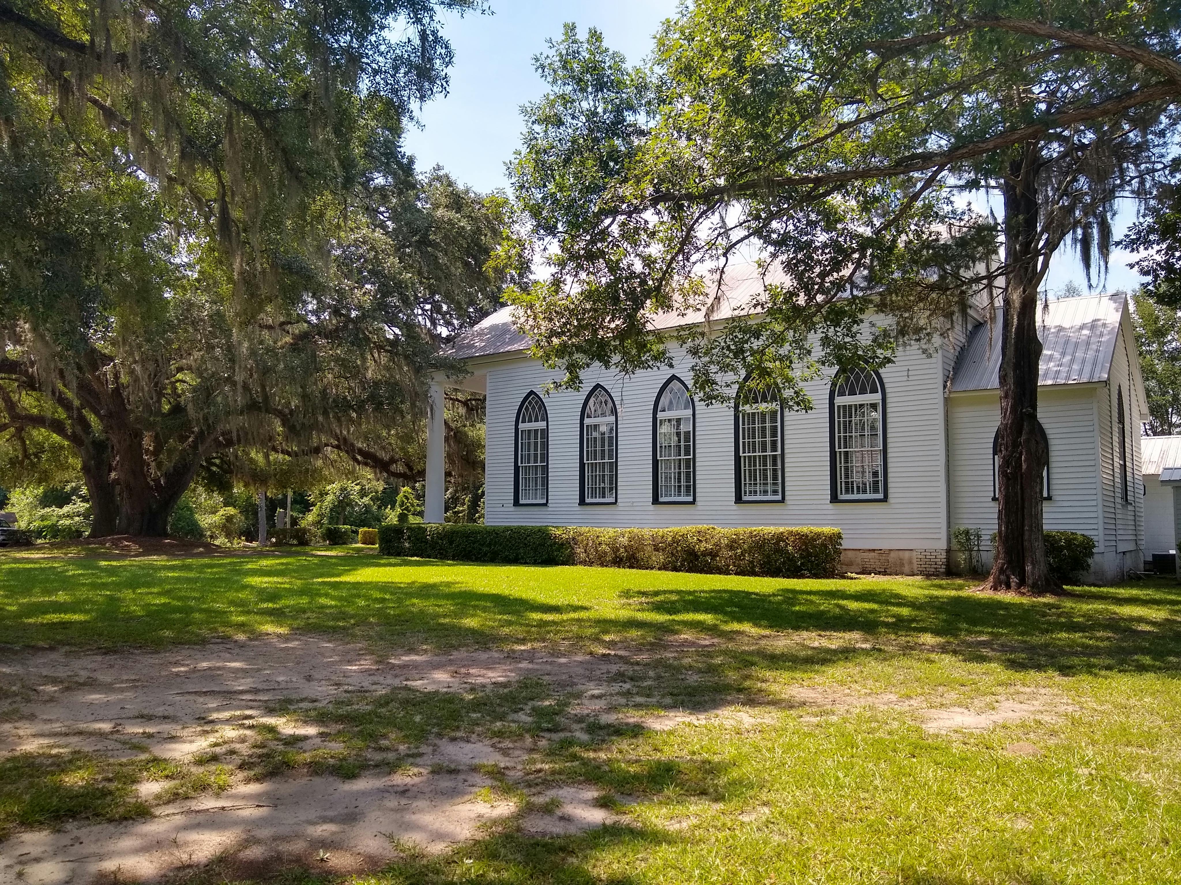 A charming white wooden church surrounded by lush trees in Garnett, South Carolina.