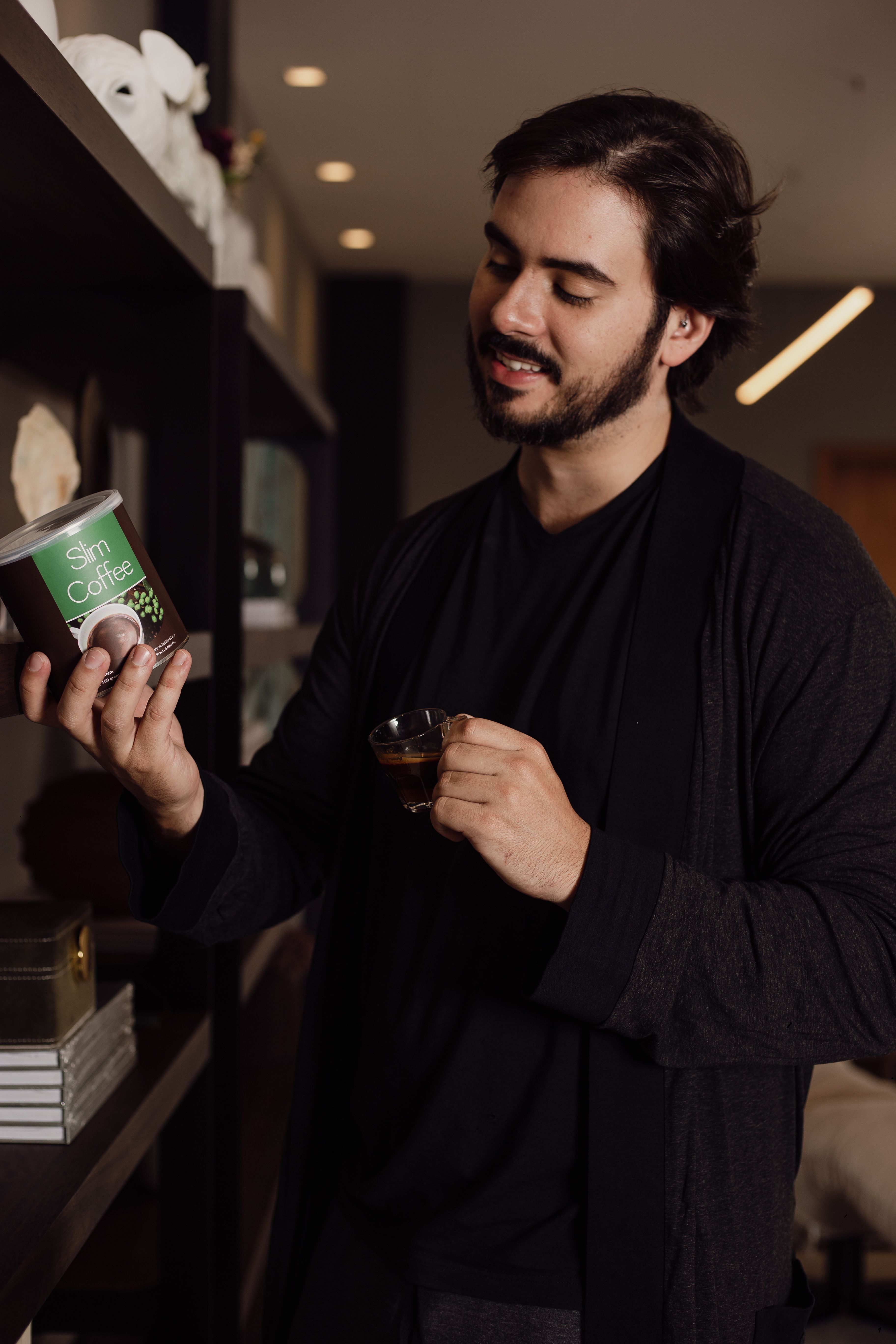 Smiling man holding coffee cup, enjoying a moment indoors with relaxed atmosphere.