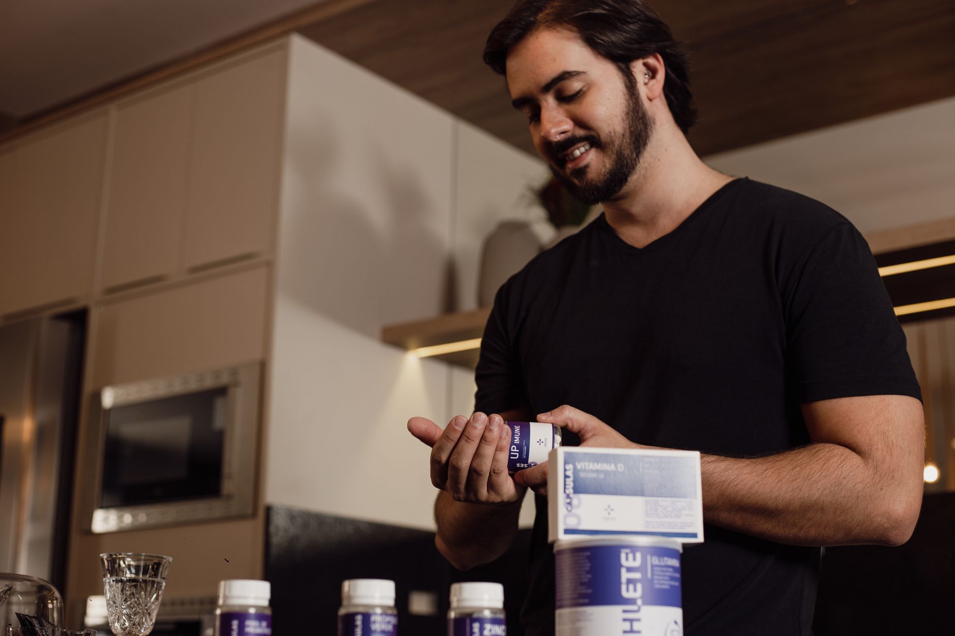 CJC 1295 Ipamorelin Review: Benefits for Americans 1 Man in kitchen holding and reviewing a bottle of supplements, indicating health-conscious lifestyle.