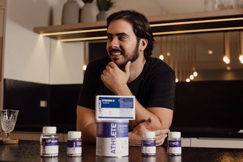 Man Sitting by the Table Surrounded by Bottles of Pills 