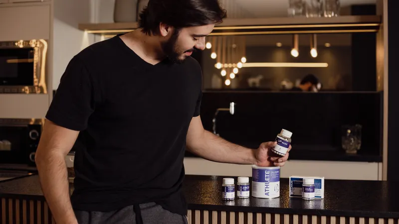 Adult man in modern kitchen examining various health supplements for fitness and wellness.