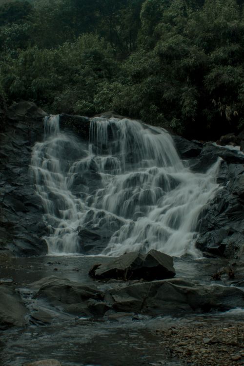 Free A peaceful waterfall cascading over rocks surrounded by lush greenery. Stock Photo