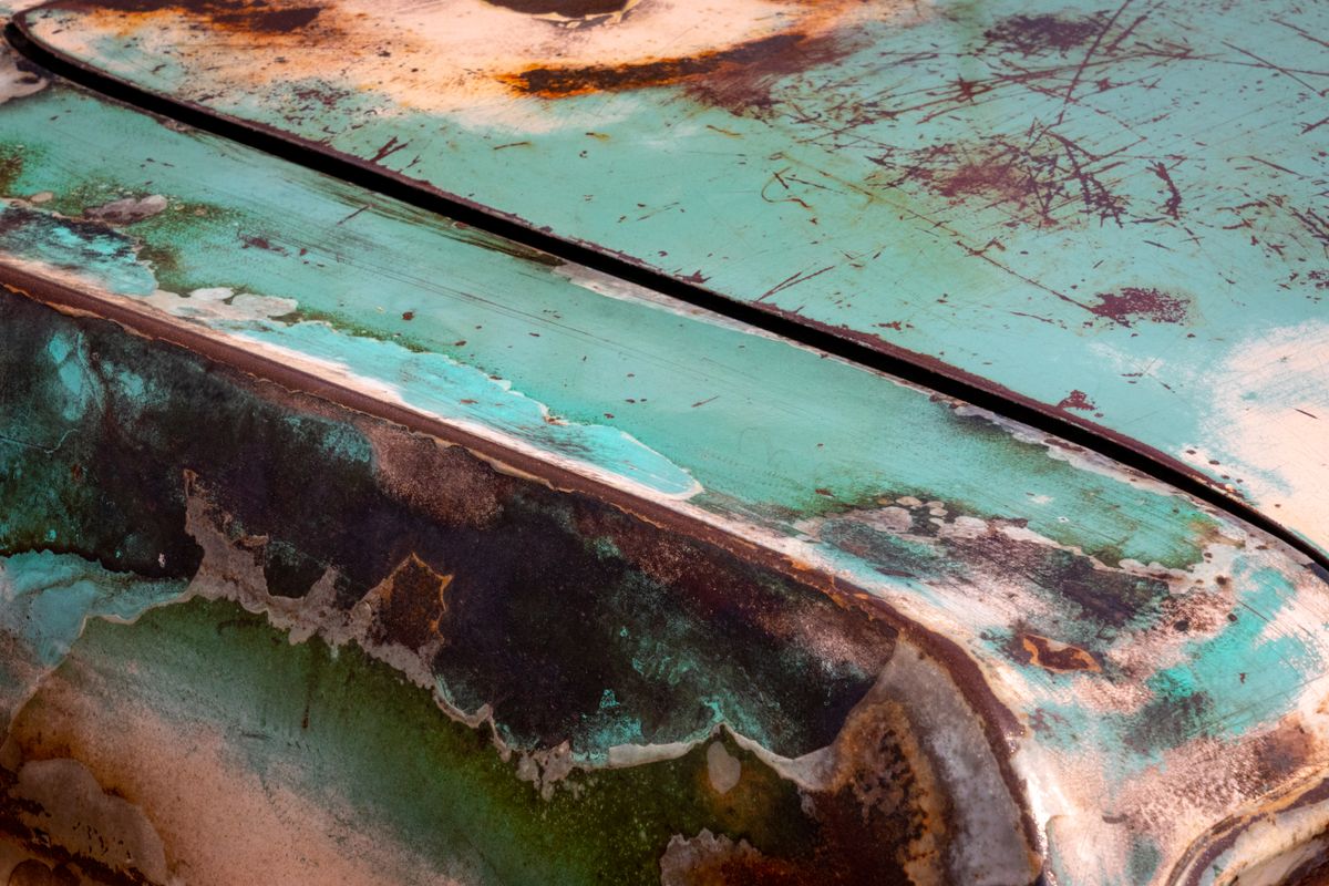 Close-up of rust and corrosion on a car fender with peeling paint