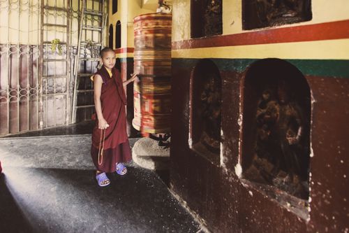 Free A young monk standing by a prayer wheel inside a Tibetan monastery. Stock Photo