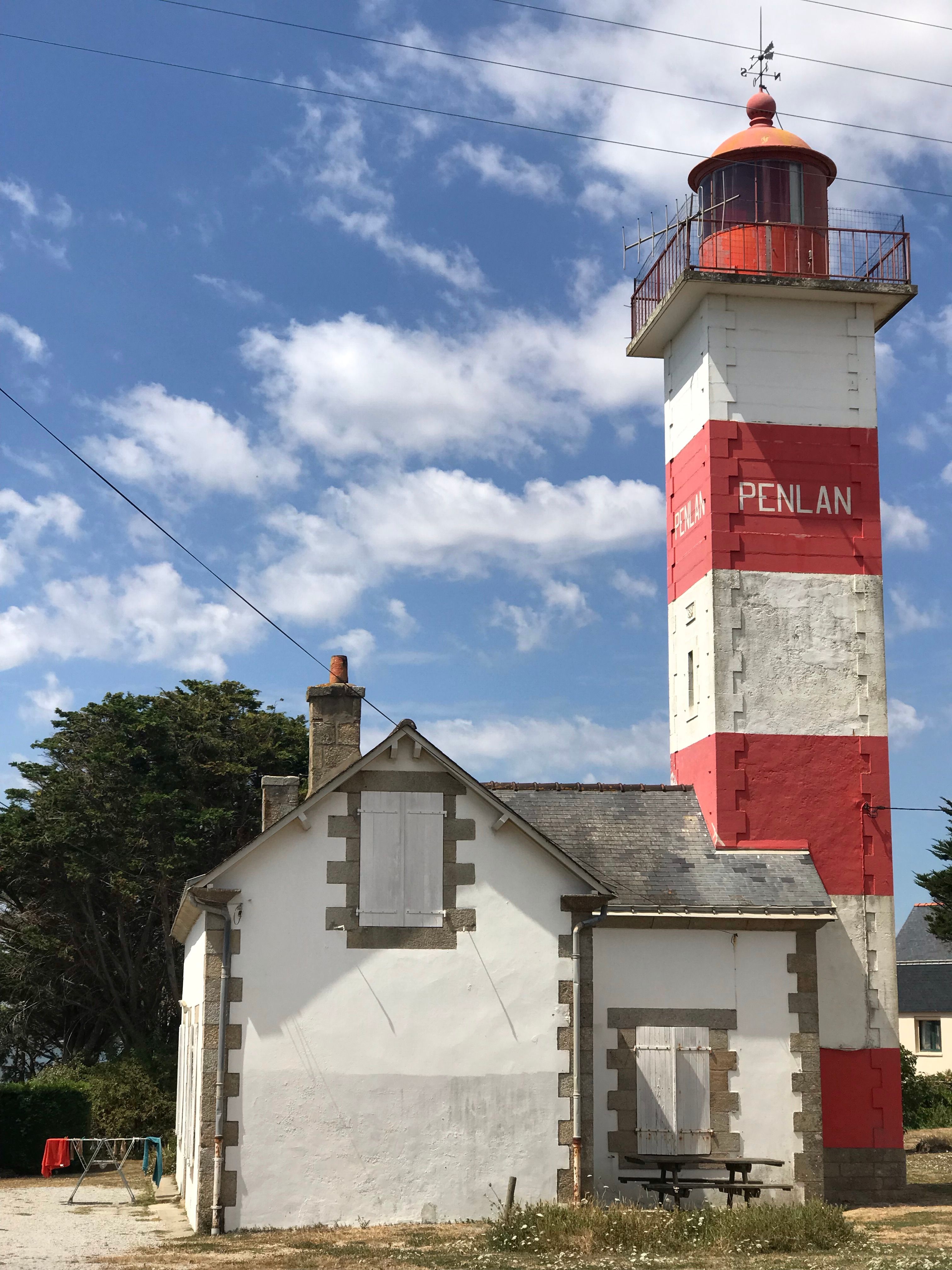 Historic Pen Lan Lighthouse in Brittany stands under a vibrant blue sky.