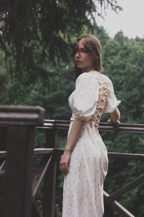 A Woman in White Dress Standing Near the Railing