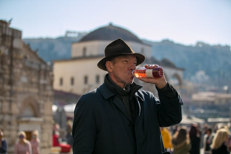 Man Drinking From Bottle On City Street