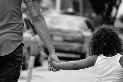 Grayscale Photography of Father and Daughter Holding Each Other While Walking