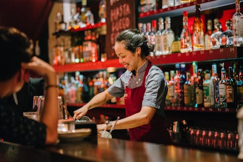 Free Woman Bartender Smiling While Mixing Liqueurs Stock Photo