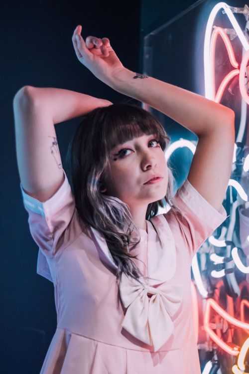 Free Stylish woman in pink dress posing with vibrant neon lights. Perfect for fashion and lifestyle themes. Stock Photo