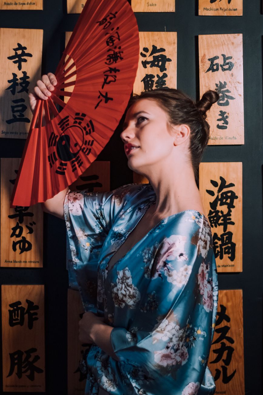 Portrait of a woman in a floral kimono holding a red hand fan, showcasing traditional Asian culture.