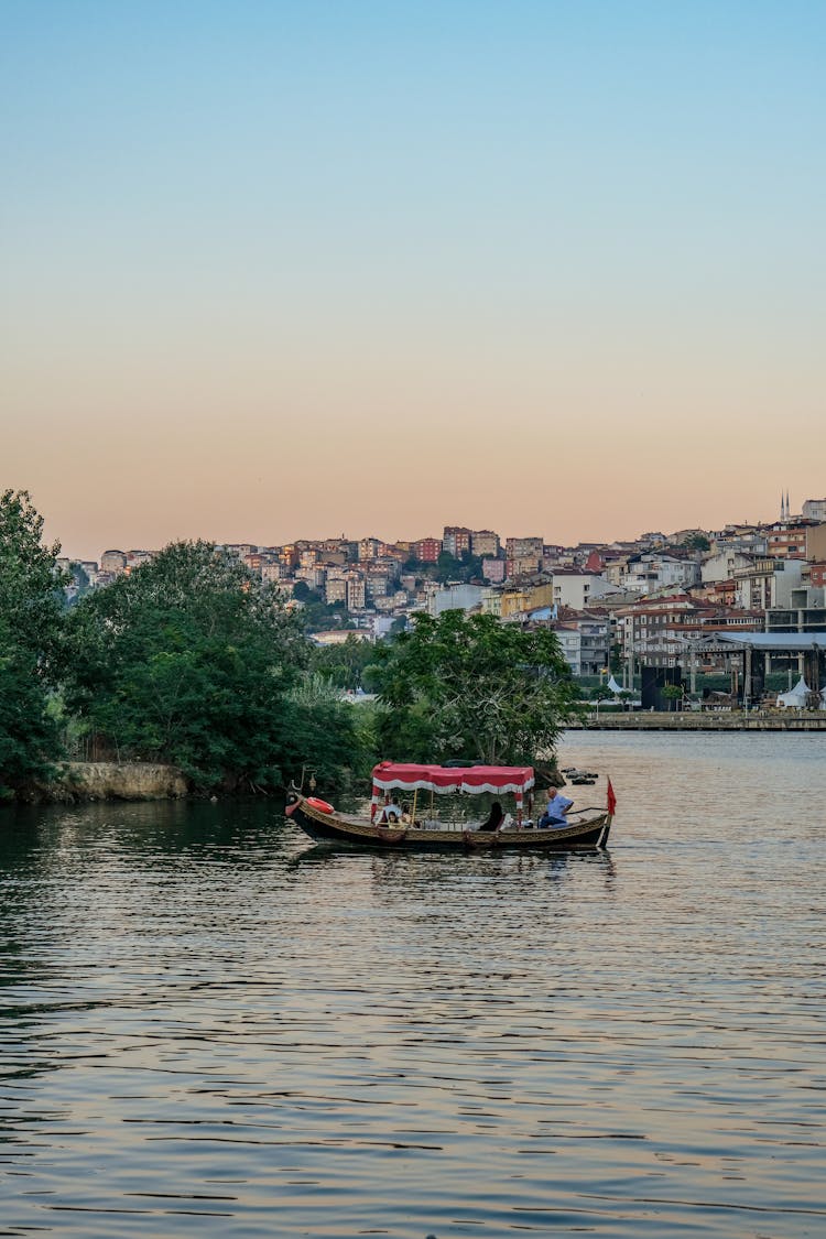 People Boating Near City At Sunset