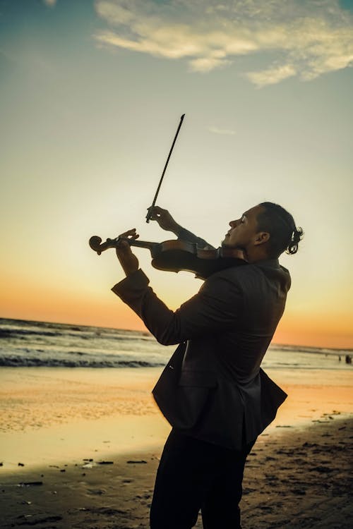 Photo of a Man Playing a Violin at the Beach