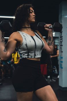 Strong woman exercising with weights in a gym, displaying confidence and focus.