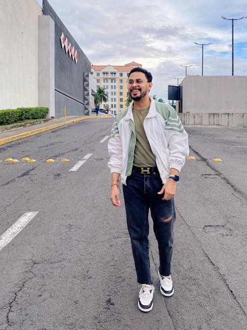 Man in White and Green Jacket Standing on Concrete Road