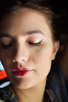 Close-up portrait of a woman with closed eyes in soft lighting, reflecting calmness.