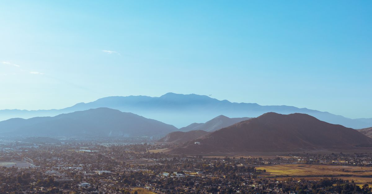 A stunning aerial view of mountains embracing the city under a blue sky.