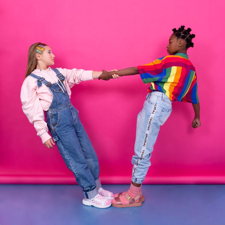 Girls In Casual Wear Holding Hands On Pink Background