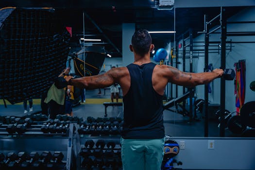 Adult male working out with dumbbells in a gym, focused on building strength and fitness.