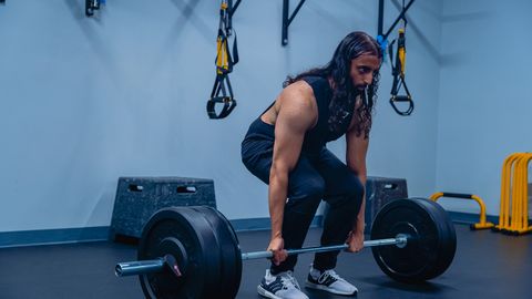 A man performing deadlifts in a gym, showcasing strength training and fitness routines.