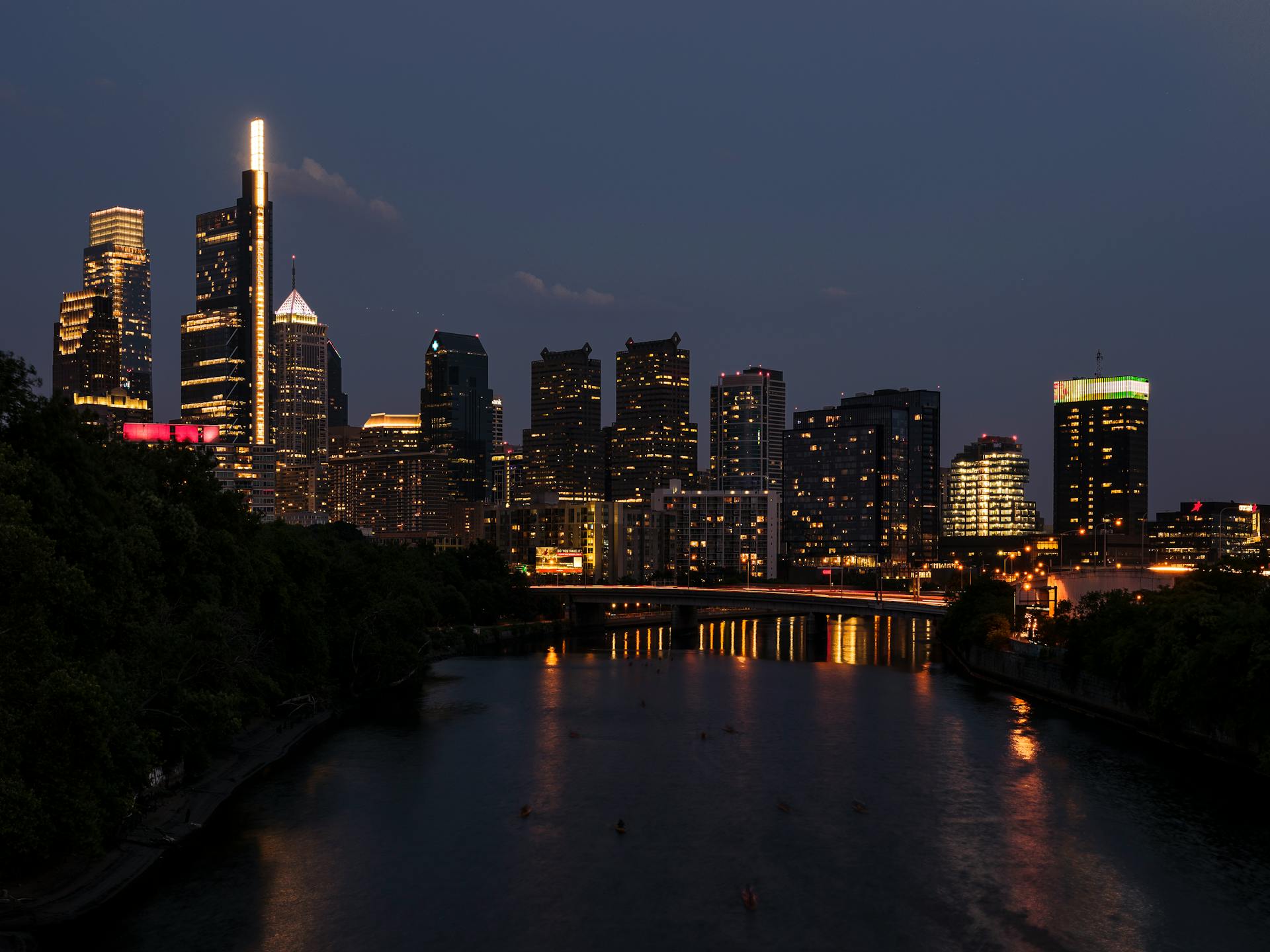 Beautiful view of Philadelphia city skyline at night with illuminated skyscrapers and reflected lights.