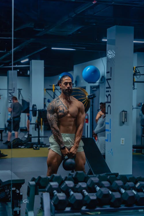 Shirtless Man Lifting Kettlebell at the Gym