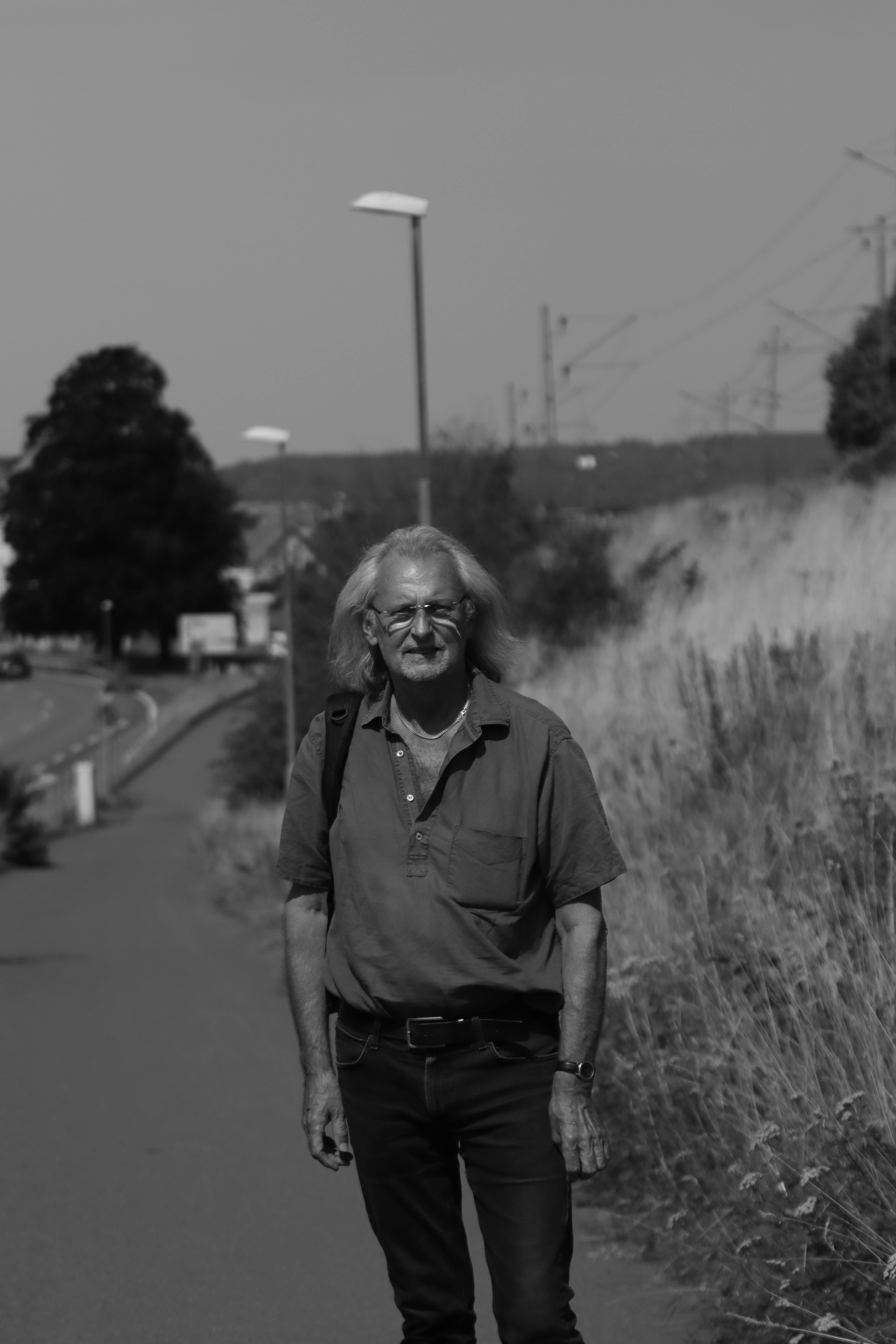 Black and white portrait of an elderly man walking beside a road in Jönköping, Sweden.