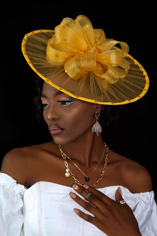 Free Stunning portrait of an African woman wearing a yellow hatinator and elegant jewelry. Stock Photo