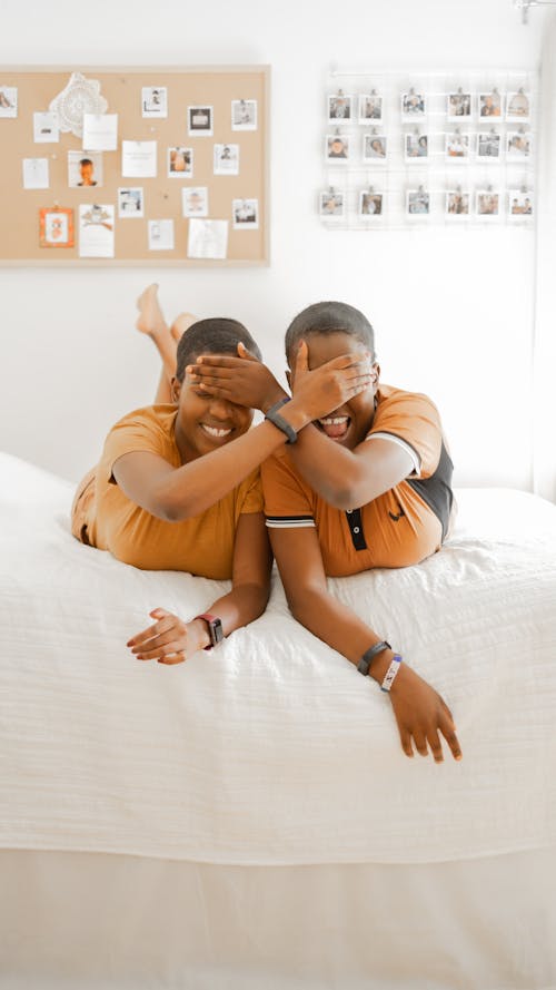 Happy People Lying on the Bed while Covering their Eyes Using their Hands